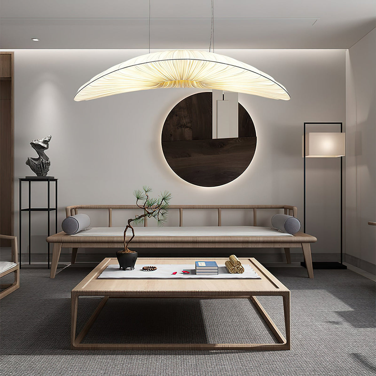 Above a low wooden table and a daybed, a Clérachic pendant with a cream pleated shade hangs near a round mirror.