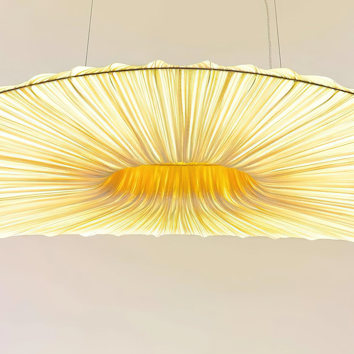 Close view of the pleated ribs and the golden centre of this Clérachic pendant shade, with the cables above.