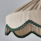 Close view of the pleated beige fabric and scalloped green braid at the lower edge of this Clérachic pendant.