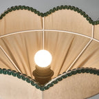 Looking up inside this Clérachic pendant at a round white bulb, the white ribs and the green scalloped trim.