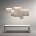 Five Clérachic fabric pendants of different sizes overlapping in a cluster above a pale stone bench, on a soft grey backdrop.