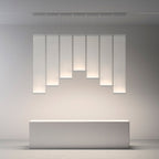 Seven Clérachic fabric panel pendants of graduated lengths lit in a row above a plain white block, on a pale grey wall.