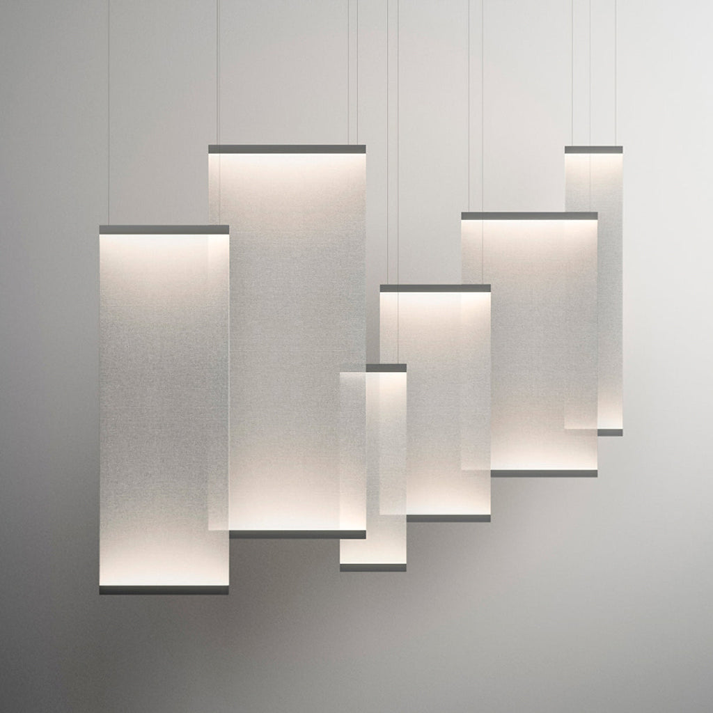 Six Clérachic fabric pendants of different sizes overlapping and lit, hung at varied heights against a pale grey backdrop.