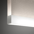 Close view of the white bottom bar on this Clérachic fabric pendant, where it meets the woven fabric, with bright light along the underside.