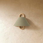 Clérachic wall sconce in sage green fabric with a wood ring bracket, shown unlit against a warm plaster wall.