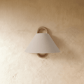 Clérachic wall light with a pale cream fabric cone shade on a wood ring mount, unlit against a soft plaster wall.