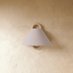 Clérachic wall sconce with a plain blush pink fabric cone shade on a solid wood ring bracket, unlit on a plaster wall.