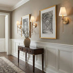 Clérachic sconces with gold-toned arms in an entry hall, hung beside framed architectural prints above a dark console table.