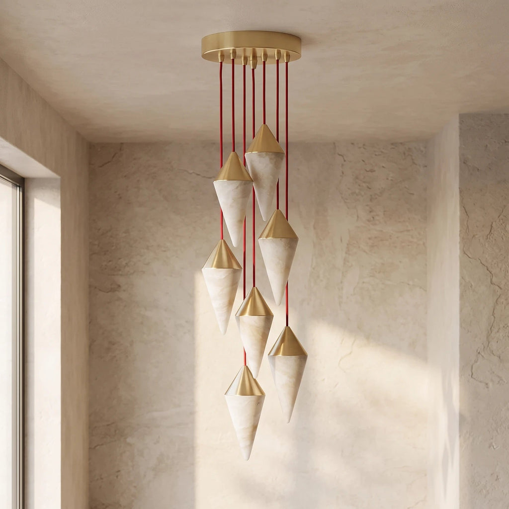 Brass-capped alabaster drops on this Clérachic chandelier hang in a sunlit plastered corner, casting long shadows.