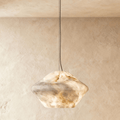 Clérachic alabaster pendant with a faceted double-cone shade of veined cream stone, glowing warm on a slim cable.