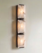 Clérachic three-panel alabaster wall light in dark metal, lit, three stacked stone panels on a slim backplate