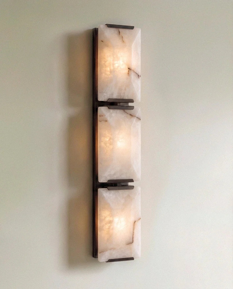 Clérachic three-panel alabaster wall light in dark metal, lit, three stacked stone panels on a slim backplate
