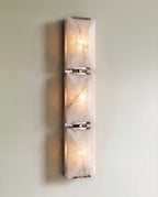 Clérachic three-panel alabaster wall light in polished steel, lit, three glowing stone panels joined by bright clips