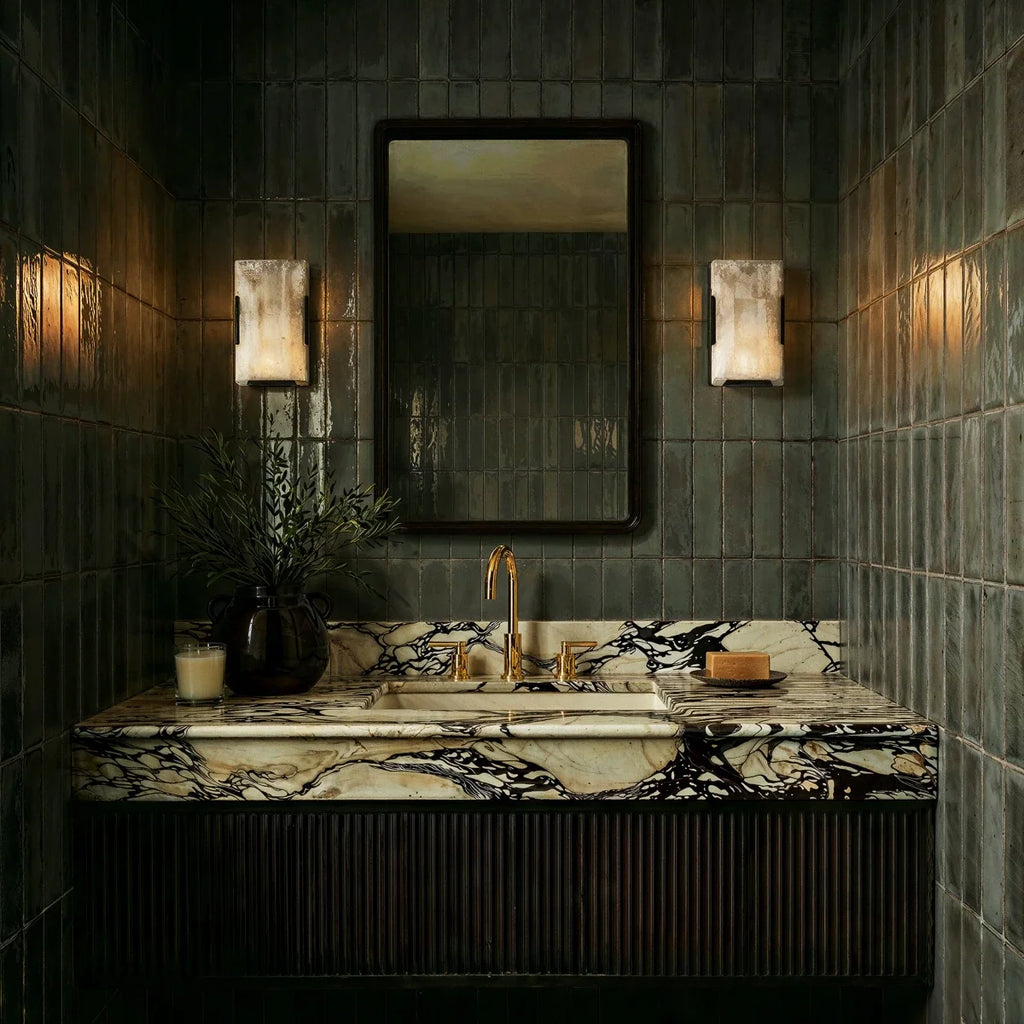 Clérachic alabaster wall lights flanking a mirror above a marble vanity in a dark green tiled washroom