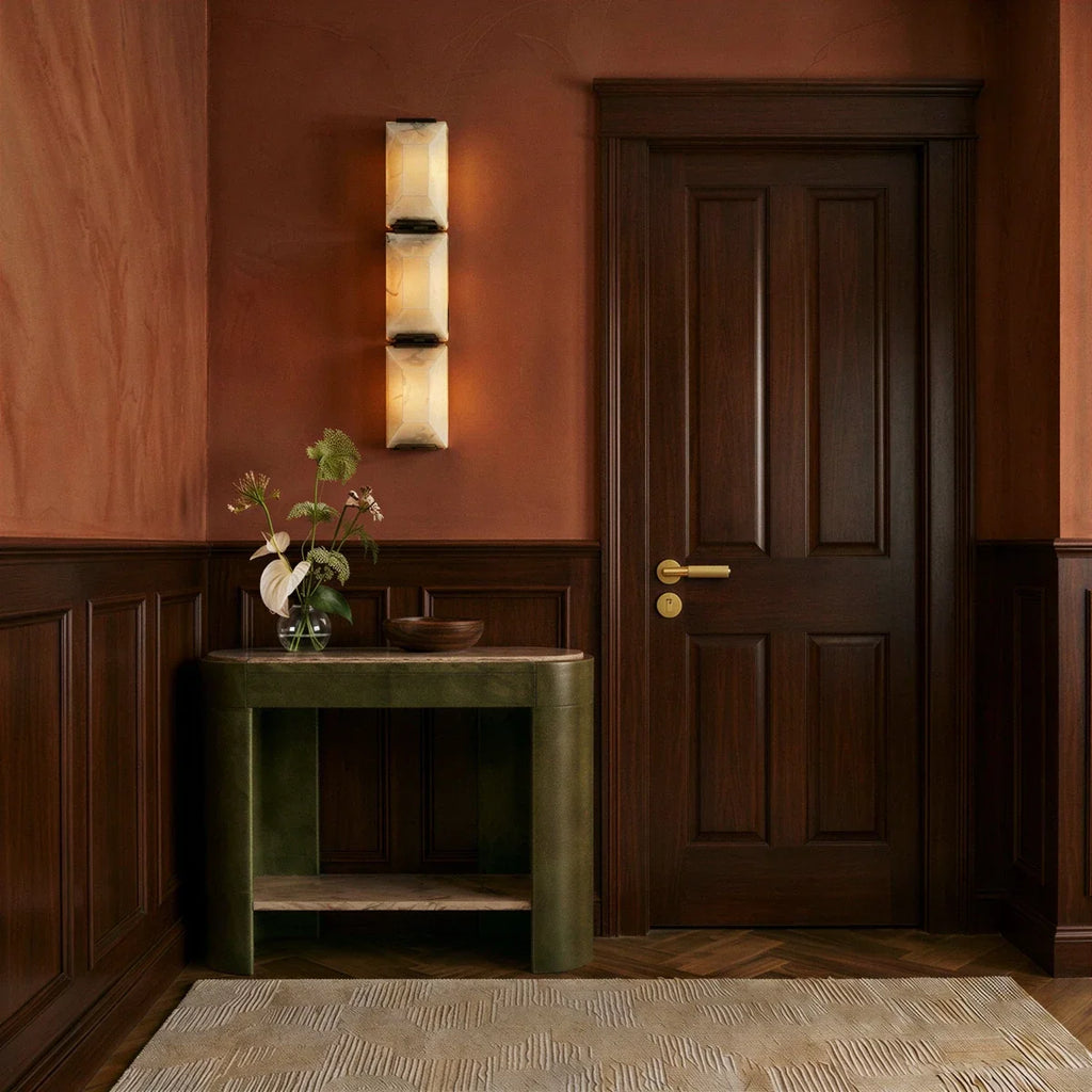 Clérachic three-panel alabaster wall light on a terracotta hallway wall beside a panelled door and a green console