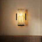 Clérachic single alabaster wall light with black clips, lit, its amber-veined stone glowing on a warm beige wall