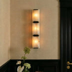 Clérachic three-panel alabaster wall light with black clips on a linen-textured wall beside a dark panelled door