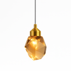 Clérachic faceted crystal pendant light lit warmly, its amber glow caught in the cut facets beneath a brushed gold cap.
