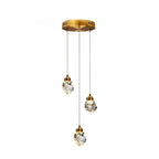 Clérachic three-head round crystal pendant light with faceted drops at staggered heights below a gold circular canopy.