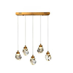 Clérachic five-head linear crystal pendant light with faceted drops at staggered heights below a long gold bar canopy.