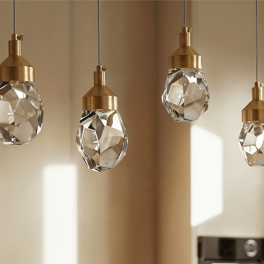 Close crop of Clérachic faceted crystal pendant lights in a row, brushed gold caps and cut facets in soft window light.
