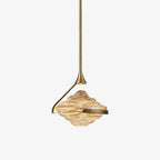 A faceted amber glass shade with a gold arm and slim gold rod hangs against a plain white backdrop, shown as this Clérachic pendant.