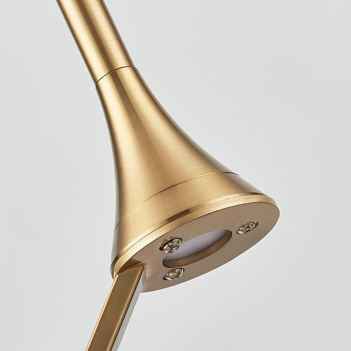 Close view of the brushed gold flared joint where the rod meets the arm, with a small round fitting below, on this Clérachic pendant.