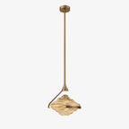 A faceted amber glass pendant hangs from a small gold ceiling plate on a slim rod against a pale grey backdrop, from Clérachic.