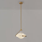 A faceted clear glass pendant with a gold arm and rod hangs against a grey wall, lit white, from Clérachic.