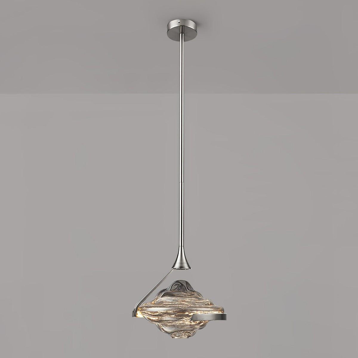 A faceted pendant with a smoke grey top and amber lit glass hangs from a chrome rod against a grey wall, from Clérachic.