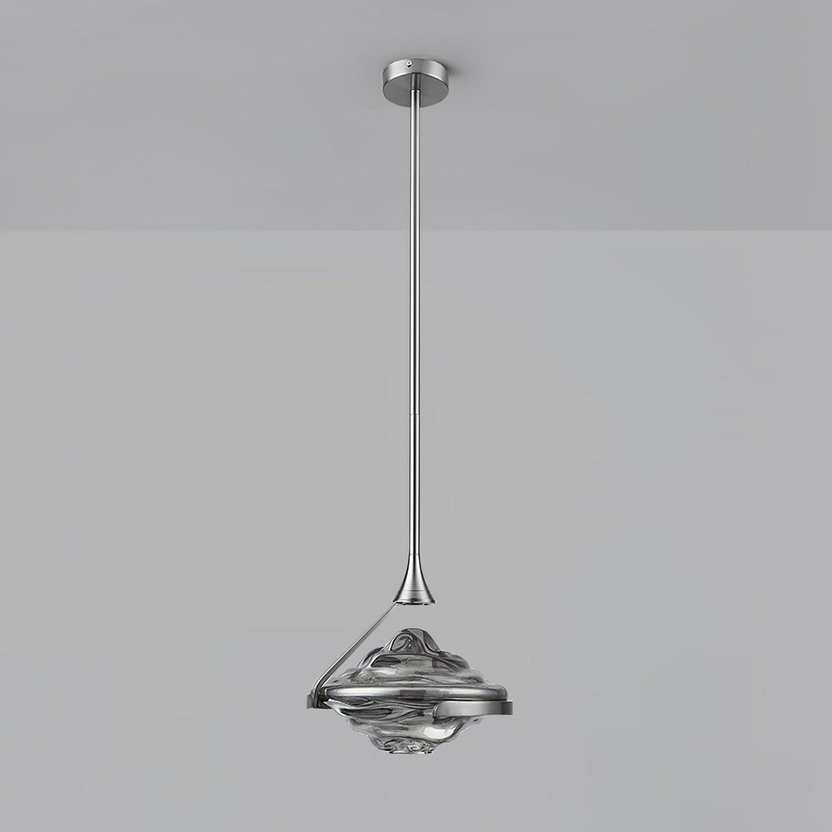 A faceted smoke grey glass pendant on a chrome rod and ceiling plate hangs against a pale grey wall, from Clérachic.