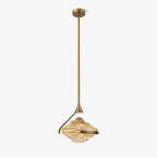 A faceted amber glass pendant with a gold arm and rod hangs against a plain white backdrop, with a small ceiling plate above, from Clérachic.