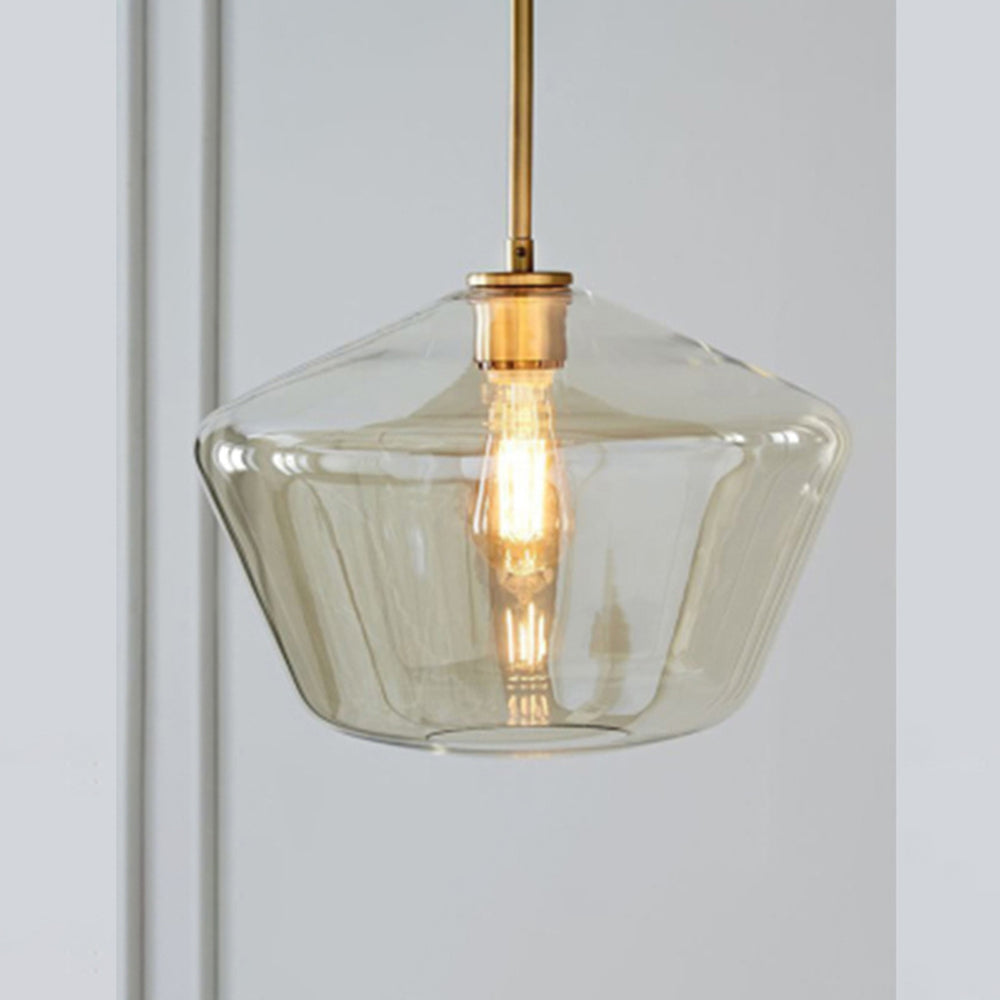 The amber flared bowl of the Clérachic faceted glass pendant light, warm light pooling inside the honey-toned glass.