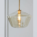 The amber flared bowl of the Clérachic faceted glass pendant light, warm light pooling inside the honey-toned glass.
