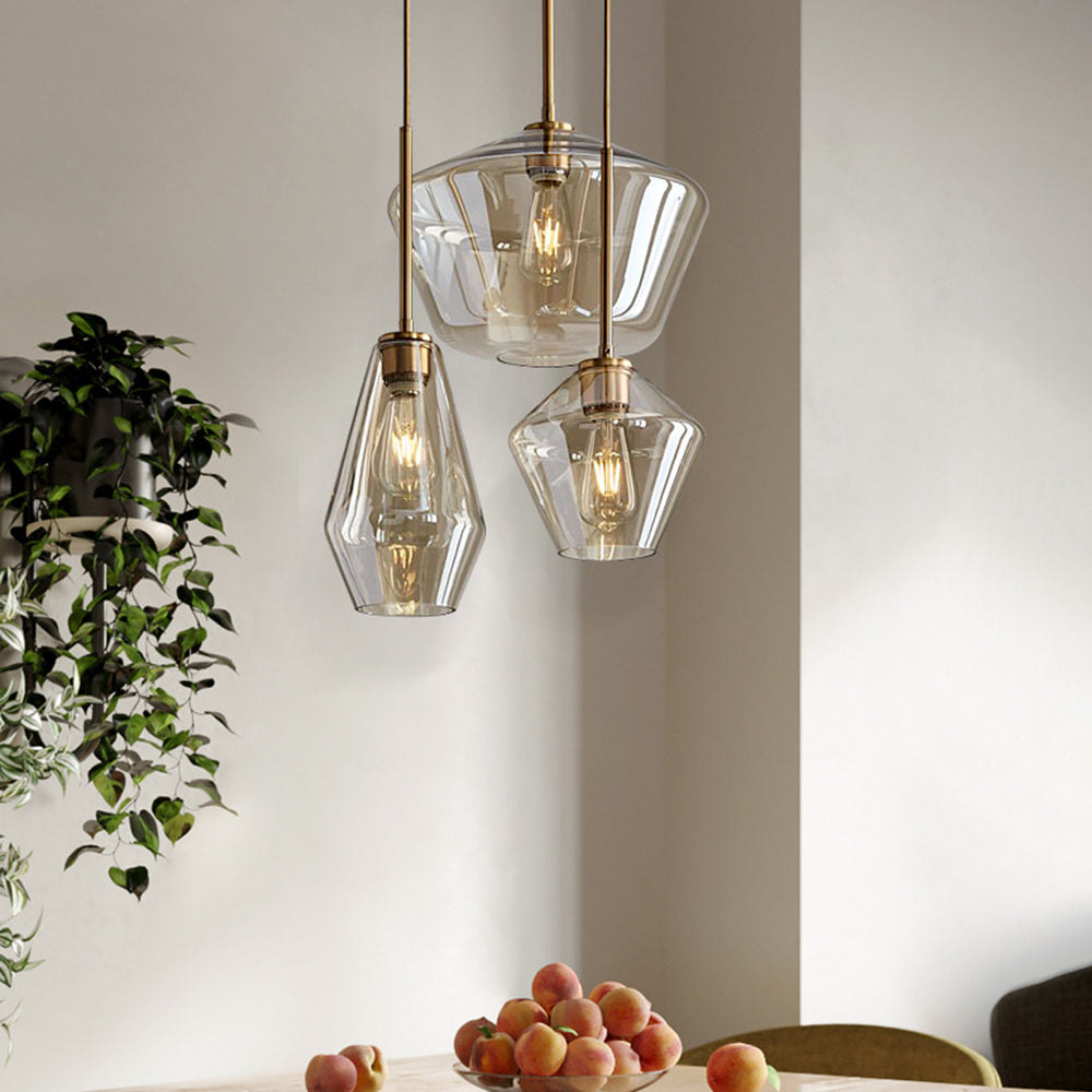 Three Clérachic faceted glass pendant lights above a dining table with peaches, trailing greenery on the wall behind.