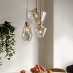 Three Clérachic faceted glass pendant lights above a dining table with peaches, trailing greenery on the wall behind.