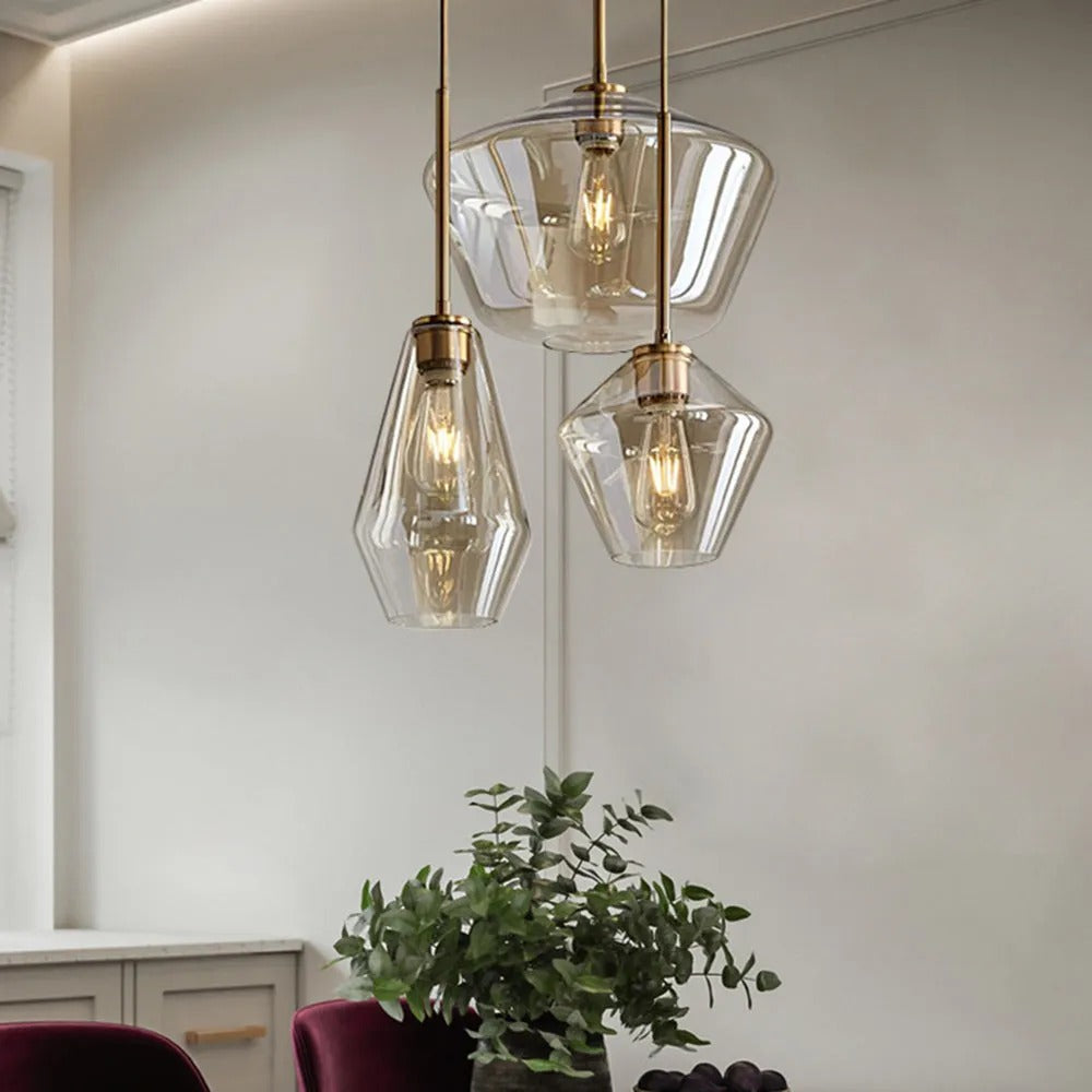 Clérachic faceted glass pendant lights grouped over a kitchen corner, three amber shades above a potted eucalyptus.