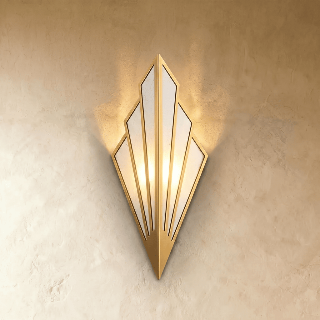 Clérachic Art Deco wall lamp in gold, a fan of linen panels in a slim metal frame, glowing warm on a limewashed wall.