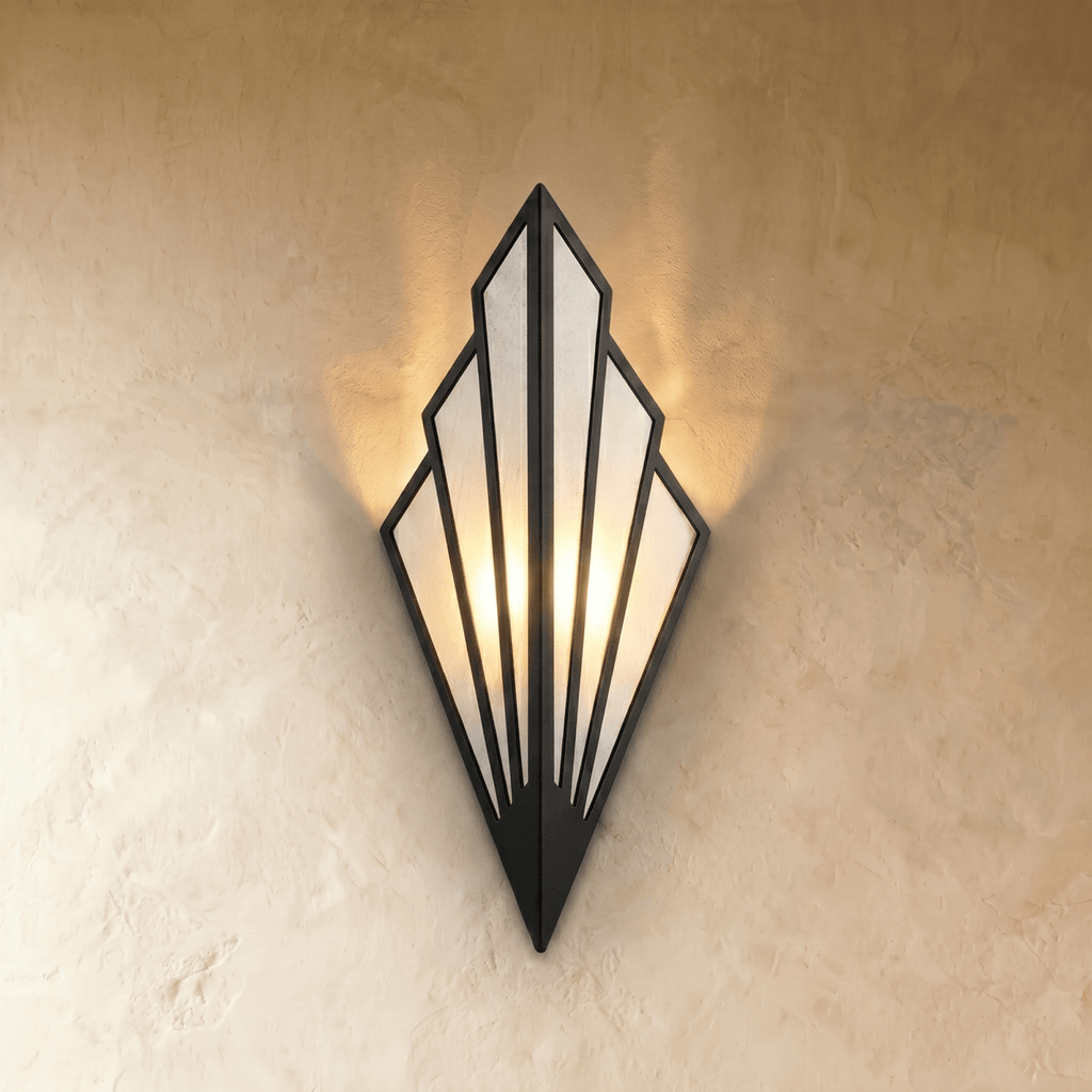 Clérachic Art Deco wall lamp in black, a fan of linen panels in a slim iron frame, lit warm against a textured wall.
