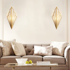 Pair of Clérachic gold Art Deco wall lamps flanking a cream wall above a buttoned taupe sofa and a glass coffee table.