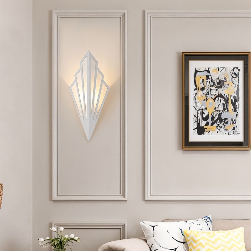 Clérachic white Art Deco wall lamp lit warm inside a panelled wall frame, with abstract art and cushions in the living room.
