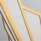 Clérachic gold wall lamp macro showing the brushed gold-tone metal frame around woven off-white linen panel texture.