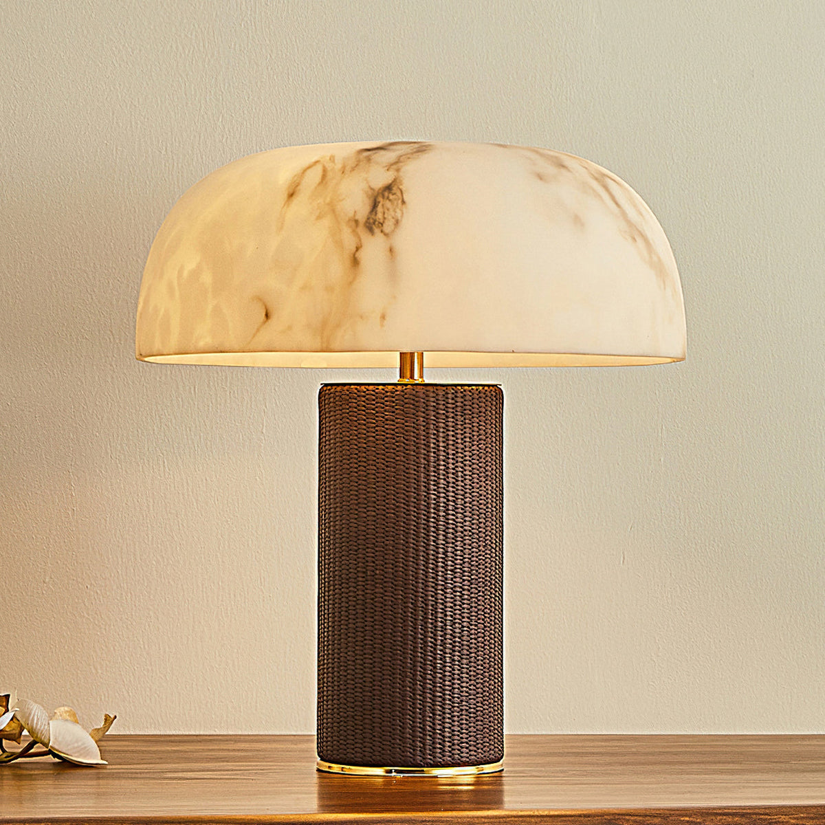 Close view of the translucent domed shade and the dark woven leather base of this Clérachic lamp, on a wooden table.