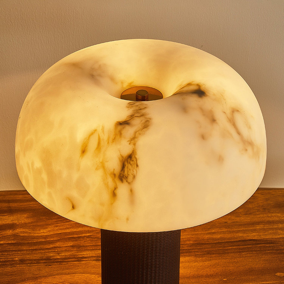 Close view of the glowing, veined domed shade on this Clérachic lamp, with the top of its dark woven base at the bottom.