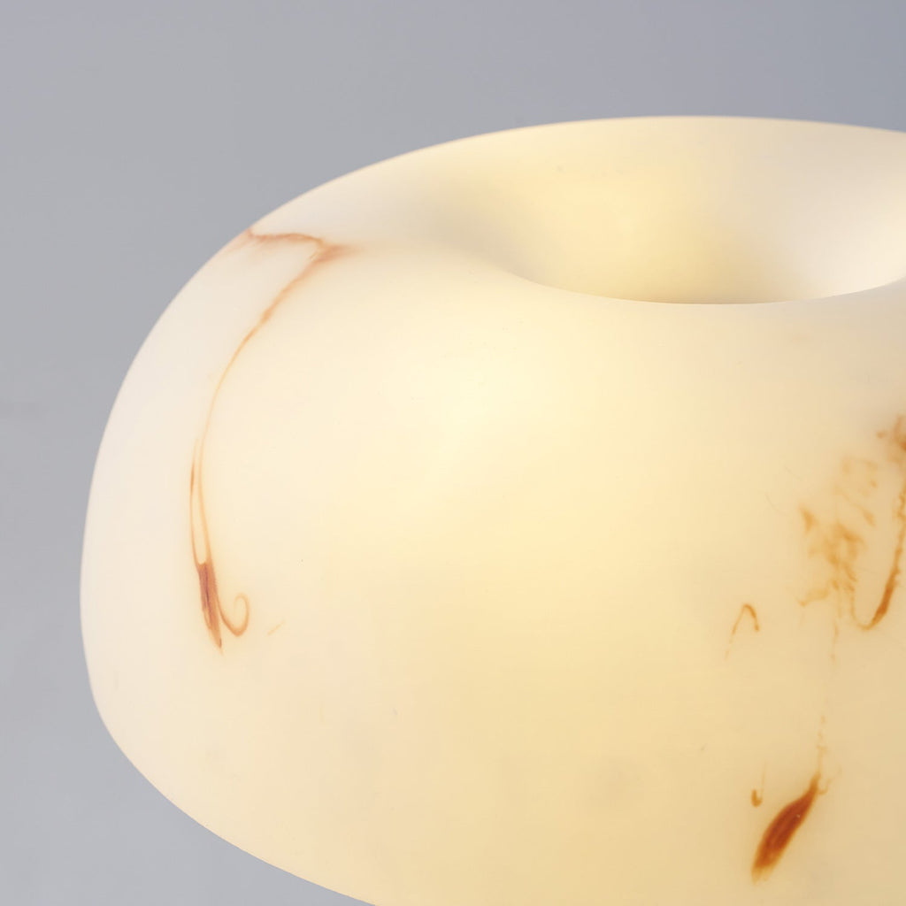 Close view of the lit, rounded shade of this Clérachic lamp, with swirls of rust-coloured veining in the white.