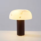 A Clérachic table lamp lit on a white surface, with a glowing veined shade above a dark woven base.