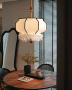 Clérachic feathered lantern pendant light centred over a round wood dining table with black spindle-back chairs and a tall ornate mirror behind.