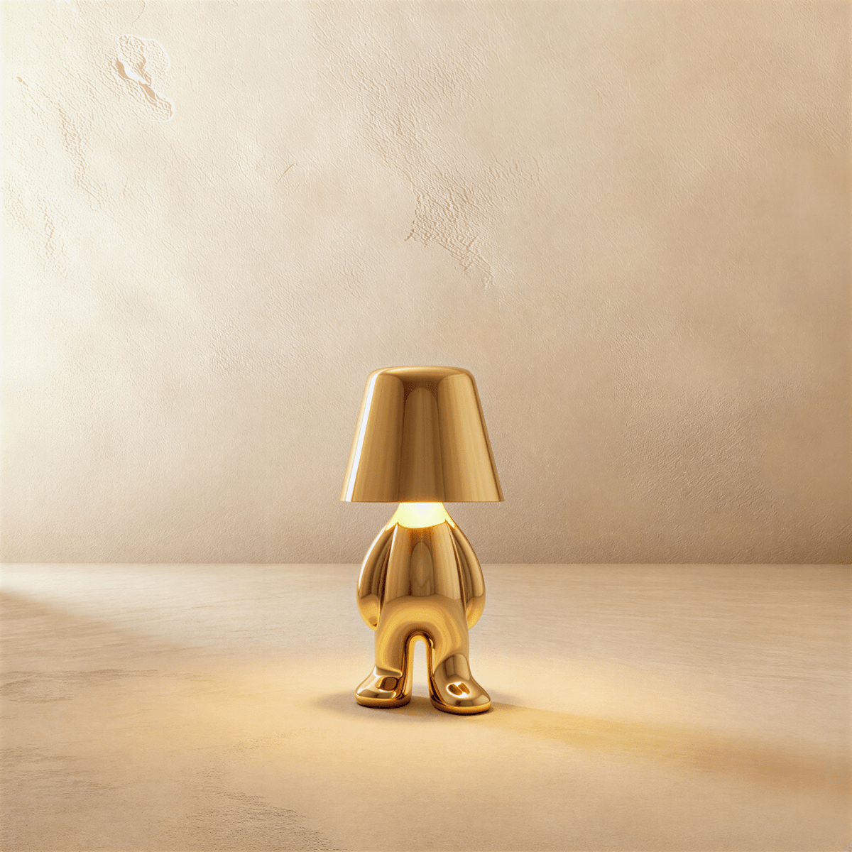 Clérachic gold figurine table lamp standing upright, warm glow beneath its tapered shade against a plaster wall.