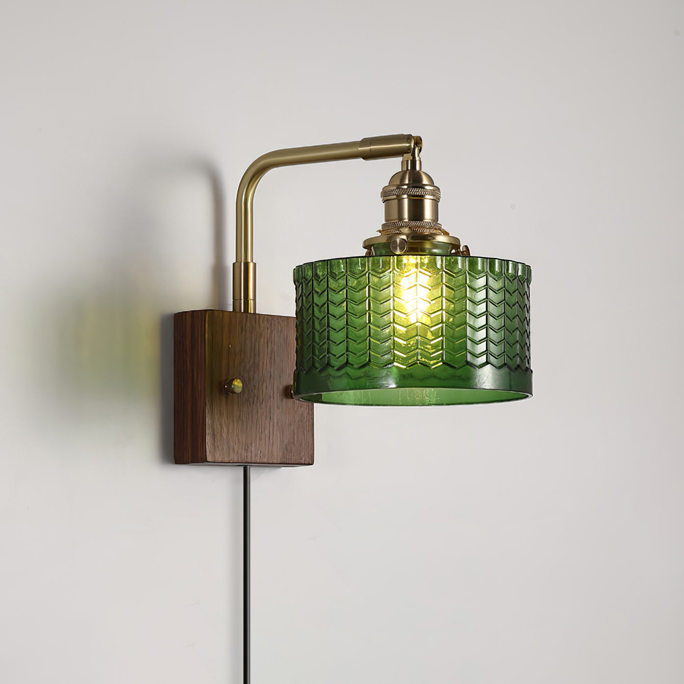 Clérachic fish-scale glass wall sconce in green, its plug-in cord running down the wall from the walnut block.