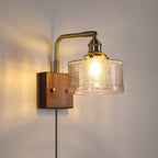 The clear glass version of the Clérachic fish-scale wall sconce, chevron relief warming to amber-gold above a plug-in cord.